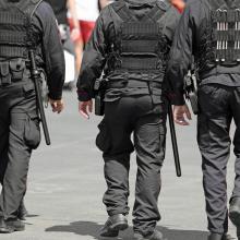 three policemen during the patrol of the city with riot uniform and batons